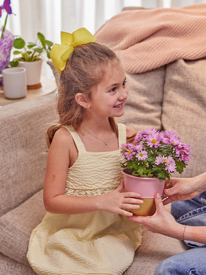 Child holding pink and gold plant container