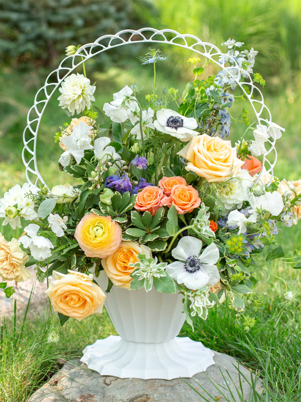 Fluted White Plastic Basket with flowers sitting on a rock