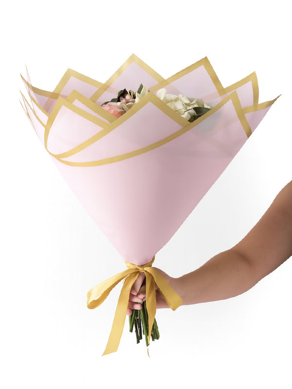 A hand holding the Madonna Wrap in pink with flowers