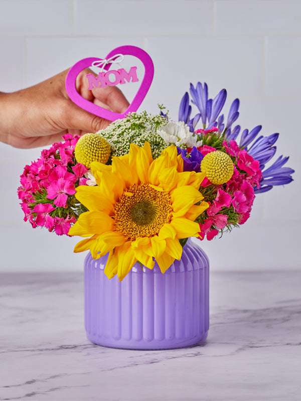 Mom's Love Pick in pink being placed to a small vase bouquet